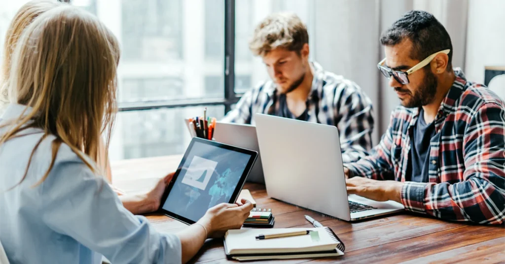 CFA candidates comparing best prep course & study materials content on laptops and tablets during a collaborative study session.